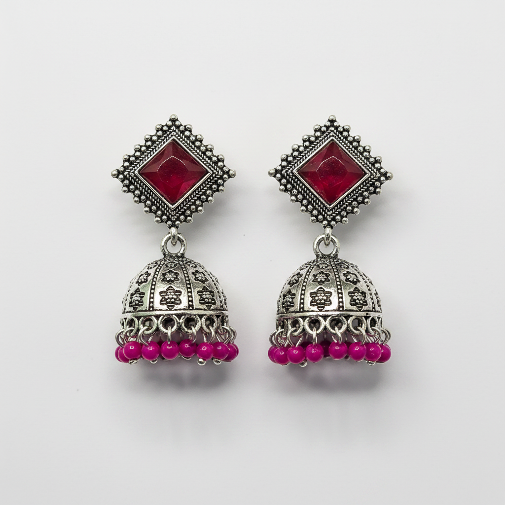 Oxidized silver ruby red stone jhumka earrings with magenta bead drops on white background